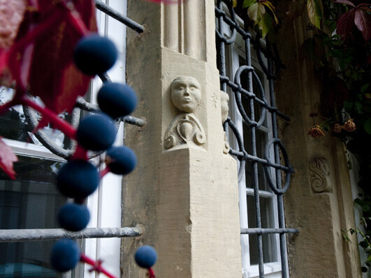 Fensterleibungen aus Sandstein mit Menschenköpfen verziert an einem mit Gittern verziertem Fenster