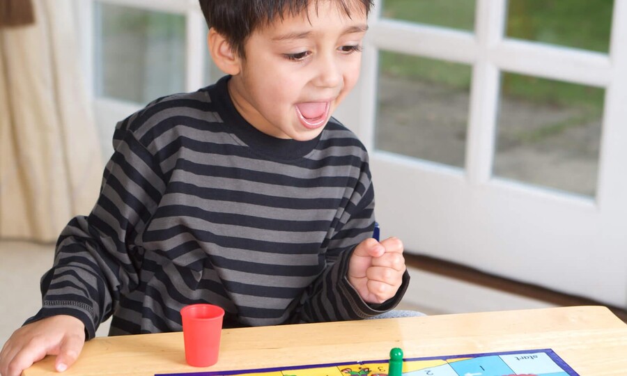 Junge, der am Tisch an einem Spielbrett sitzt