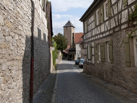 Straße mit Fachwerkhäusern und am Ende steht ein Turm
