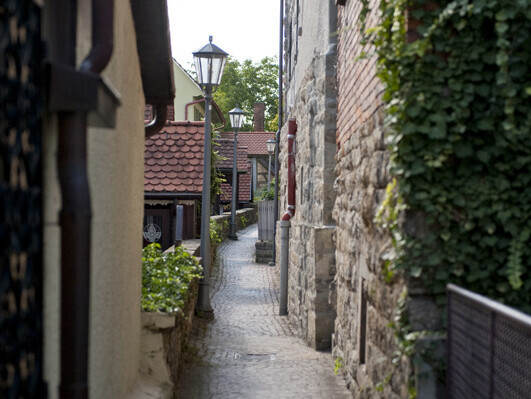 Schmaler Weg zwischen kleinen Häusern und einer Steinmauer