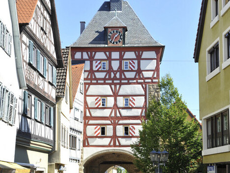 Fachwerkhäuser und Fachwerkturm in einer Fussgängerzone. Durch den Turm führt die Fussgängerzone. 