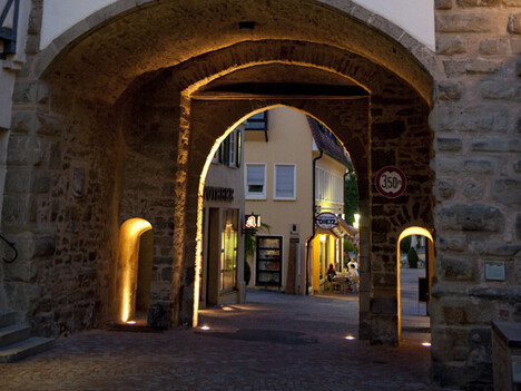 bleuchtete Torbögen durch die eine Straße läuft
