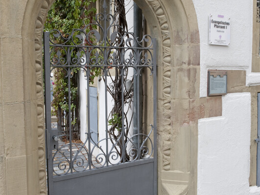 Steintorbogen mit einer verzierten Stahltüre vor einem altem Haus