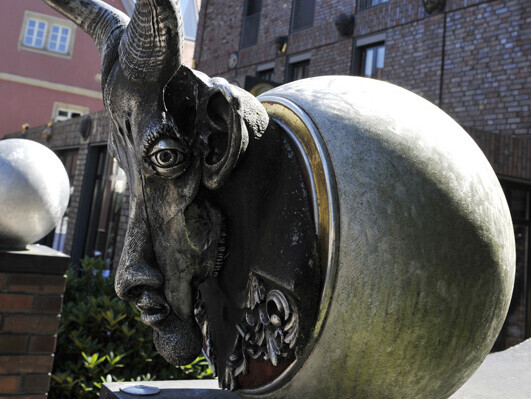 Skulpturen rund aus der ein Ziegenkof mit menschlichem Mund und Nase schaut