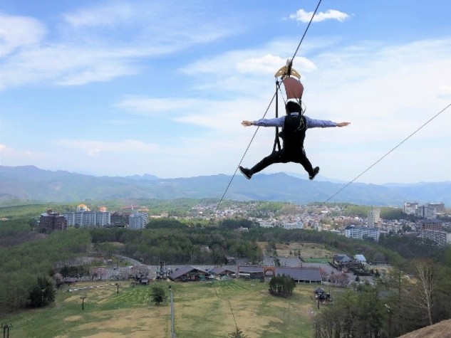 A man glides over a zipline above a city