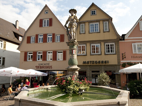 Brunnen mit Männlich Figur vor einem Caffe 