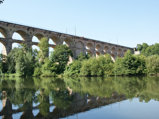 Brücke für Züge mit vielen Bögen darunter fließt ein Fluss