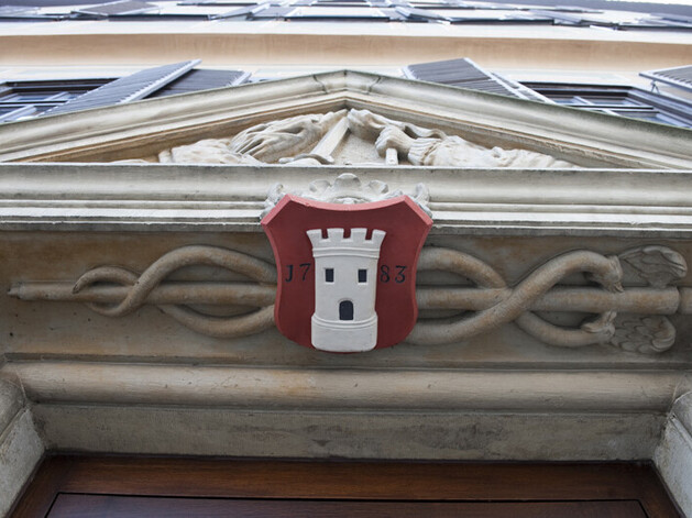 Rpotes Wappen mit weißem Turm an einem verzierten Türrahmen